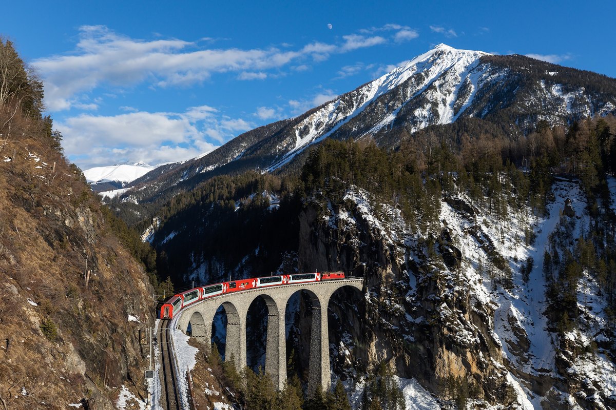 The red Glacier Express train crossing the Landwasser Viaduct in the Swiss Alps