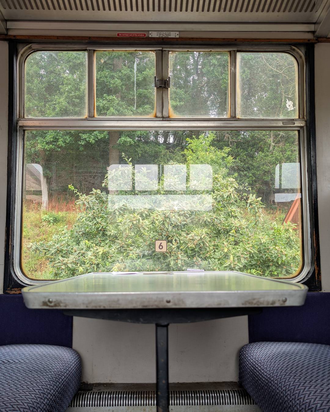 The view of passing countryside from a cosy vintage train compartment window